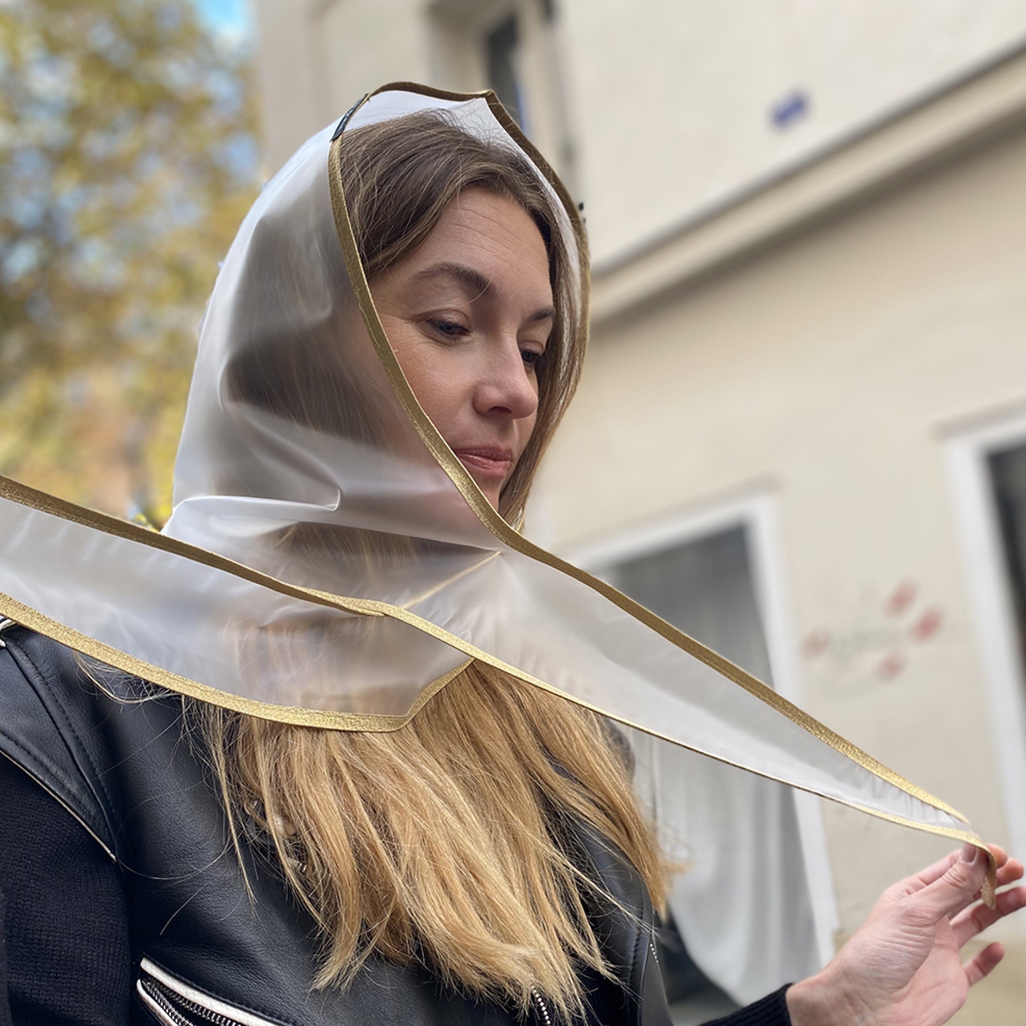 Blonde Frau knotet Regenkapuze Transparent aus dem Allthatiwant Shop zum Schutz vor Regen