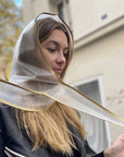 Blonde Frau knotet Regenkapuze Transparent aus dem Allthatiwant Shop zum Schutz vor Regen