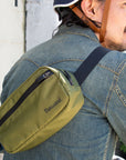 Umhängetasche Thousand in Oliv an Mann mit Jeansjacke und Fahrradhelm