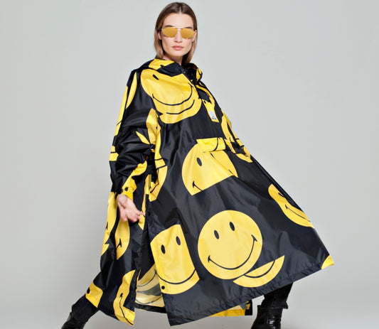 Rainkiss All Smiley Regenponcho mit gelben Smileys auf schwarzem Mantel Model mit Sonnenbrille
