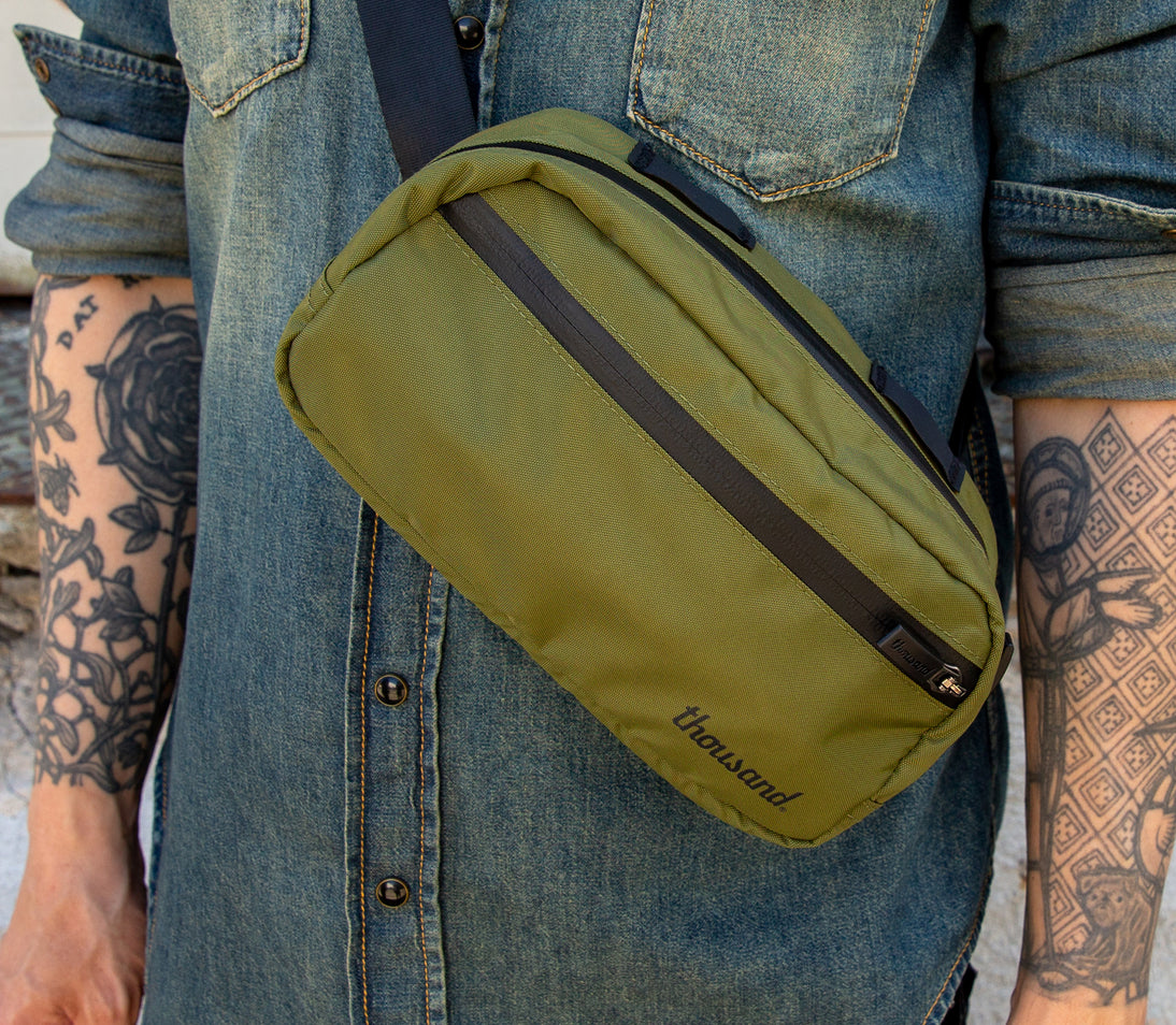 Crossbody Bag von Thousand in Oliv getragen von Mann mit Jeanshemd und Tattoos